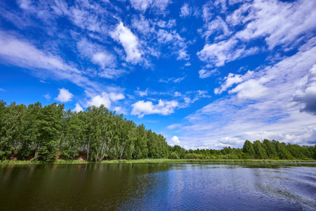 Beautiful summer landscape of river at sunny day with sky and clouds reflection in the waterの写真素材