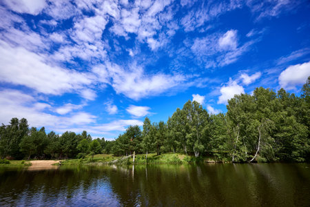 Beautiful summer landscape of river at sunny day with sky and clouds reflection in the waterの写真素材