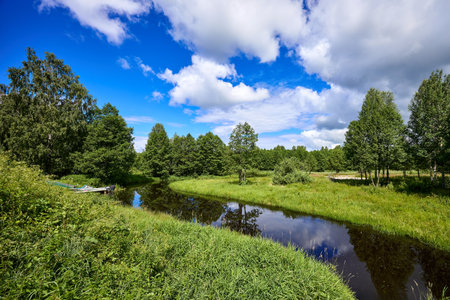Beautiful summer landscape of river at sunny day with sky and clouds reflection in the waterの写真素材