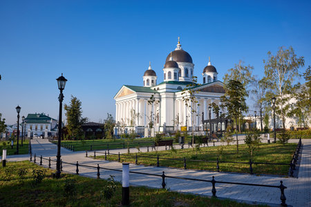 Majestic cathedral with domes against blue sky in Arzamas, surrounded by lush gardens and pathways, blending architectural beauty with tranquil urban landscaping at sunny morningの写真素材