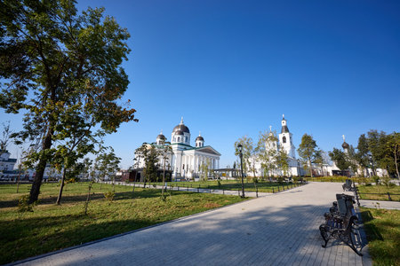 Majestic cathedral with domes against blue sky in Arzamas, surrounded by lush gardens and pathways, blending architectural beauty with tranquil urban landscaping at sunny morningの写真素材