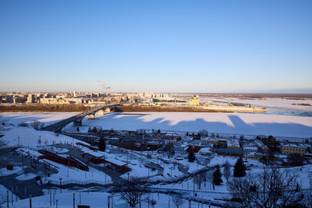 A breathtaking winter panorama of Strelka in Nizhny Novgorod, where the Oka River meets the Volga. Featuring the Kanavinsky Bridge and Alexander Nevsky Cathedral under clear blue skiesの写真素材