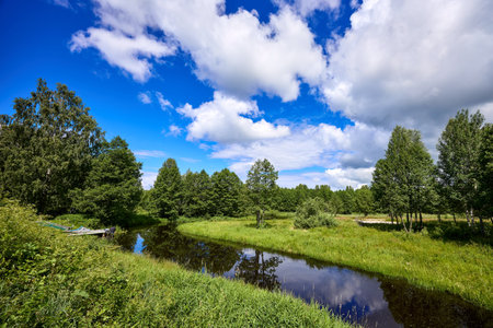 Beautiful summer landscape of river at sunny day with sky and clouds reflection in the waterの写真素材