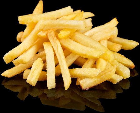 A pile of golden, crispy French fries with an oily sheen, displayed against a black background, highlighting their freshly fried texture and appetizing appeal. Perfect for fast food enthusiastsの写真素材