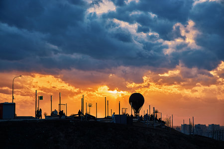 Silhouette featuring a hot air balloon set against a breathtaking sunset, vibrant clouds, and rays of sunlight, creating a dreamy and magical atmosphereの写真素材