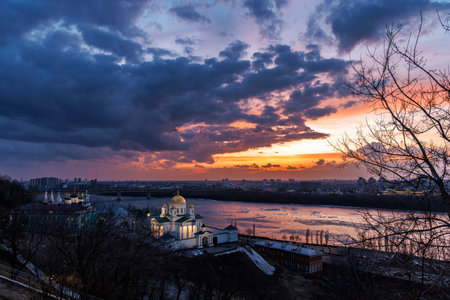 A breathtaking winter sunset over the Annunciation Monastery in Nizhny Novgorod, Russia. The golden domes contrast beautifully against the dramatic sky and the shimmering riverの写真素材