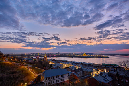 A magical twilight view of Strelka in Nizhny Novgorod, showcasing the lit-up Kanavinsky Bridge, Rozhdestvenskaya Church, and Alexander Nevsky Cathedral reflecting on the Oka Riverの写真素材