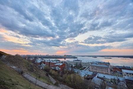 A vibrant sunset over Strelka in Nizhny Novgorod, where the Oka River meets the Volga, showcasing Alexander Nevsky Cathedral under a glowing skyの写真素材