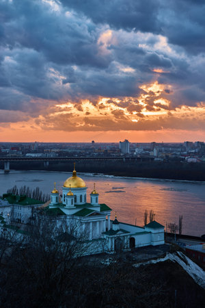 A breathtaking winter sunset over the Annunciation Monastery in Nizhny Novgorod, Russia. The golden domes contrast beautifully against the dramatic sky and the shimmering riverの写真素材