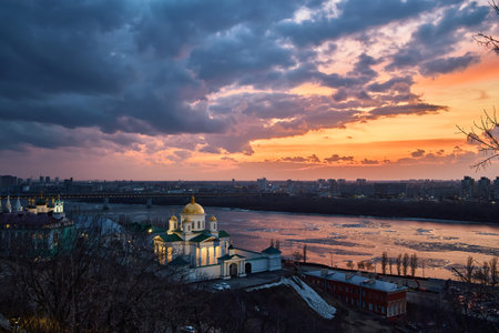 A breathtaking winter sunset over the Annunciation Monastery in Nizhny Novgorod, Russia. The golden domes contrast beautifully against the dramatic sky and the shimmering riverの写真素材