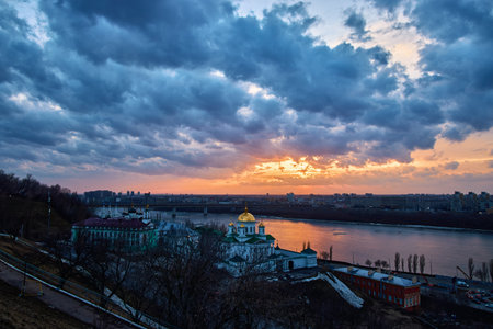 A breathtaking winter sunset over the Annunciation Monastery in Nizhny Novgorod, Russia. The golden domes contrast beautifully against the dramatic sky and the shimmering riverの写真素材