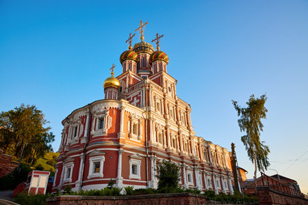The vibrant Stroganov Church, also known as the Christmas Church, glows at dusk in Nizhny Novgorod, showcasing its ornate architecture and golden domes against a clear skyの写真素材