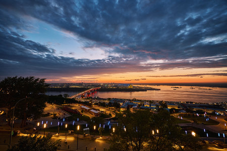 Stunning view of Kanavinsky Bridge and Alexander Nevsky Cathedral in Nizhny Novgorod at dusk, glowing city lights reflected in the river beneath a vibrant night skyの写真素材