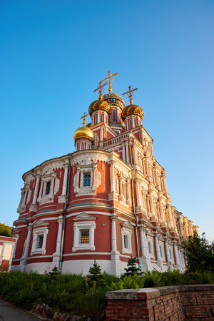 The vibrant Stroganov Church, also known as the Christmas Church, glows at dusk in Nizhny Novgorod, showcasing its ornate architecture and golden domes against a clear skyの写真素材