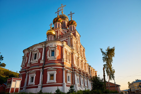 The vibrant Stroganov Church, also known as the Christmas Church, glows at dusk in Nizhny Novgorod, showcasing its ornate architecture and golden domes against a clear skyの写真素材