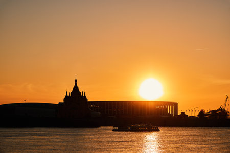 Riverboat passes by Strelka at sunset with silhouettes of Alexander Nevsky Cathedral and stadium in Nizhny Novgorodの写真素材