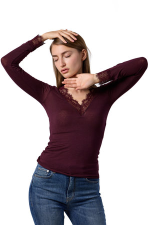 Young beauty in elegant burgundy lace top and denim jeans posing in fashion studioの写真素材