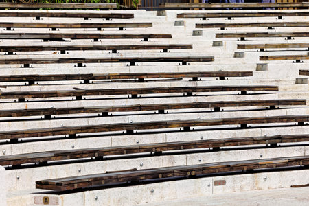 Top-down view of weathered wooden benches on tiered concrete steps â€” an abstract...