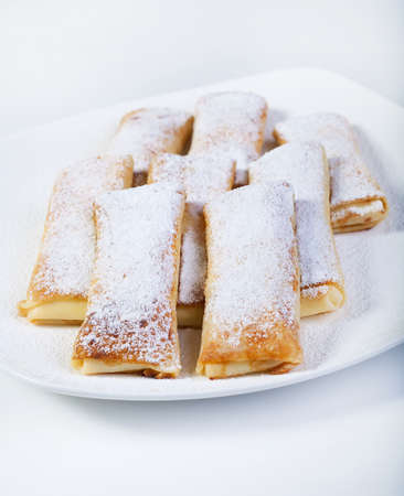 Delicious pancakes with powdered sugar on a plate on a white background