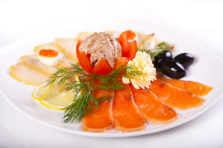 Smoked fish with olives and Lemon on a white plate.の写真素材