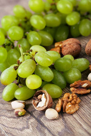 Assorted nuts with grapes on a wooden table.の写真素材