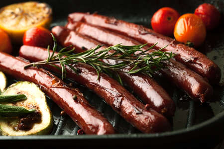 Grill sausages with vegetables, rosemary and spices in a frying pan grillの写真素材