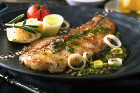 Grilled fish with lemon and rosemary in the sauceの写真素材