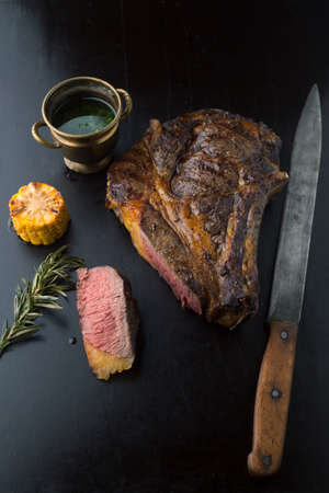 Sliced medium rare grilled Black Angus Steak Ribeye  with rosemary and corn on a dark backgroundの写真素材