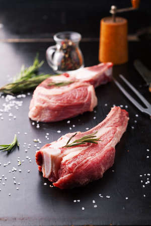 Raw beef steak with bone and rosemary on a dark backgroundの写真素材