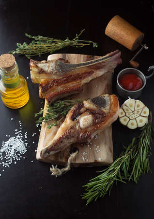 Grilled beef chops with rosemary and garlic on a wooden boardの写真素材