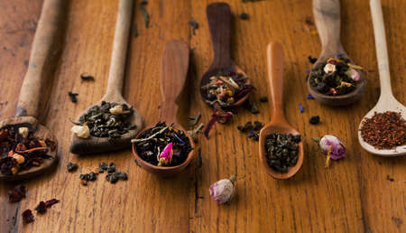 Assorted herbs and tea with a spoon on a wooden backgroundの写真素材