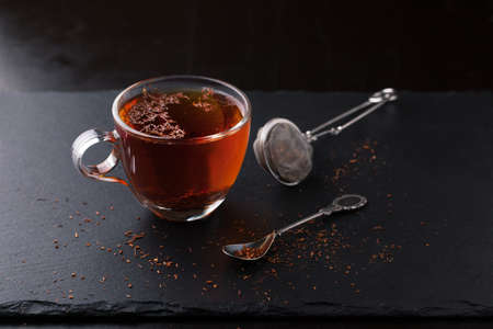 Cup of tea with a spoon and tea leaves on a dark backgroundの写真素材