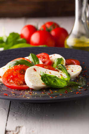 Caprese salad with mozzarella, fresh tomato and basil on a plate