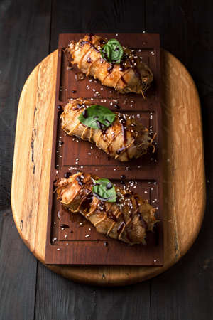 Delicious stuffed chicken roll with sauce and sesame seeds on a wooden boardの写真素材
