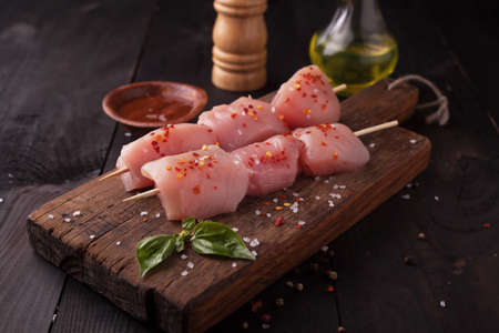Raw chicken shish kebab on skewers with spices on a wooden backgroundの写真素材