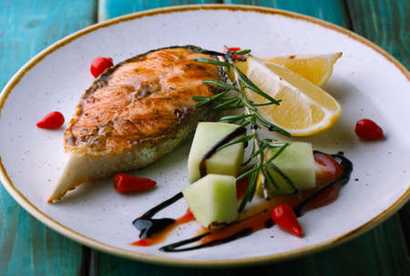 Grilled salmon on a plate with sauce and spices on a wooden backgroundの写真素材