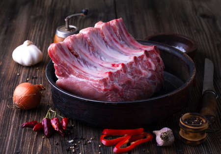 Raw pork chop with spices and herbs on a wooden backgroundの写真素材