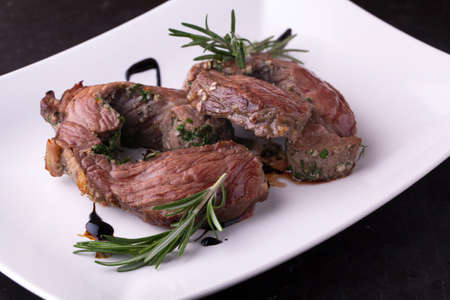 Beef roulade with smoked bacon grilled with rosemary and garlic on a plate on a wooden backgroundの写真素材