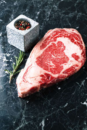 Raw beef steak ribeye loin marble on a dark marble background