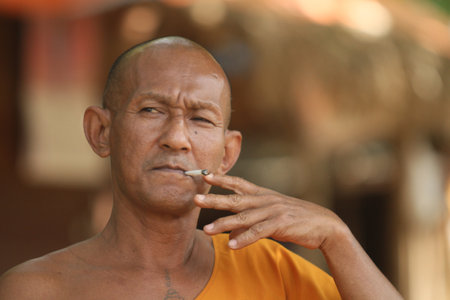 KOH CHANG, THAILAND - DECEMBER 5: Smoking a cigarette unidentified monk in a Buddhist monastery Wat Klong Prao, December 5, 2011 in Koh Chang, Thailand.のeditorial素材