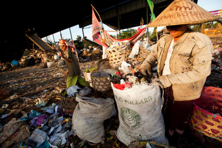 BALI, INDONESIA - APRIL 11: Poor people from Java island working in a scavenging at the dump on April 11, 2012 on Bali, Indonesia. Bali daily produced 10,000 cubic meters of waste.のeditorial素材