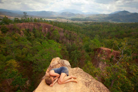Young girl lying on top of the rock in the canyon, picture of loneliness の写真素材