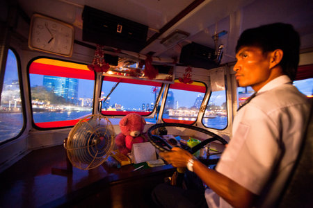 BANGKOK - APRIL 30: Unidentified driver of a water bus plying the Chao Phraya River, Apr 30, 2012 on Bangkok. Fare 10-15 baht, intervals 5 min - does boat attractive alternative ground transportation.のeditorial素材