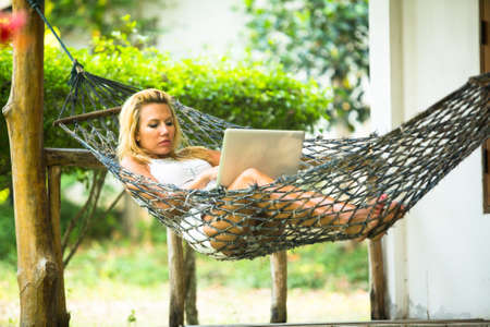 Young woman lies in the hammock with laptop.の写真素材