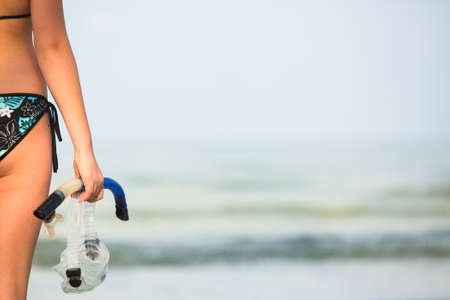 Snorkeling or diving, young woman with a snorkel and mask standing on sand and going to swim in sea ( の写真素材