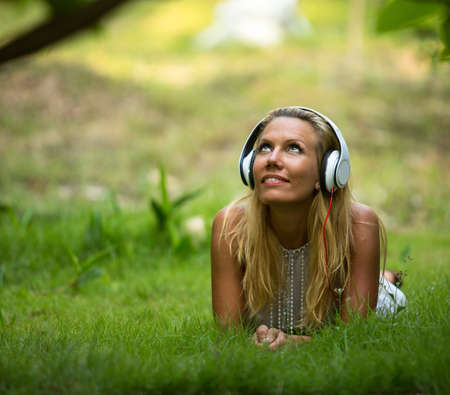 Happiness girl with headphones enjoying nature and music at sunny dayの写真素材