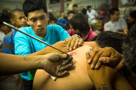 NAKHON CHAI, THAILAND - MAR 23: Unidentified monk makes traditional Yantra tattooing during Wai Kroo Master Day Ceremony in Wat Bang Pra on Mar 23, 2013 in Nakhon Chai, Thailand.のeditorial素材