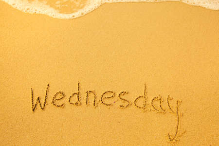 Wednesday - written in sand on beach texture.