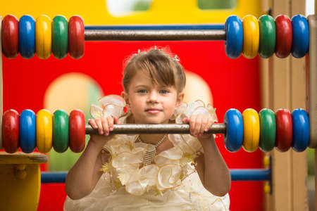 Portrait of a baby girl in an elegant dress on the playgroundの写真素材