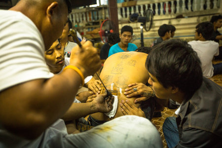 NAKHON CHAI, THAILAND - MAR 23: Unidentified monk makes traditional Yantra tattooing during Wai Kroo Master Day Ceremony in Wat Bang Pra on Mar 23, 2013 in Nakhon Chai, Thailand.のeditorial素材